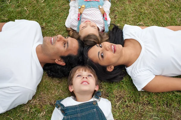 Veselý rodiče a jejich děti, ležící na trávě — Stock fotografie
