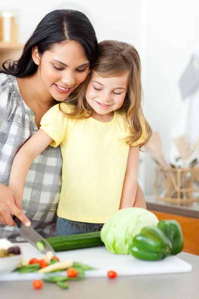 Adorable little girl cutting vegetables with her mother — Stock Photo, Image