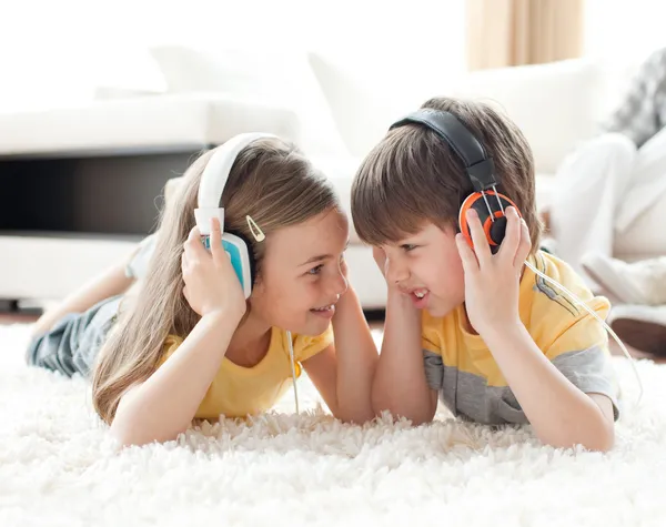 Hermanos jugando en el suelo con auriculares —  Fotos de Stock