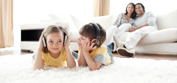 Menino e menina brincando no chão com fones de ouvido — Fotografia de Stock