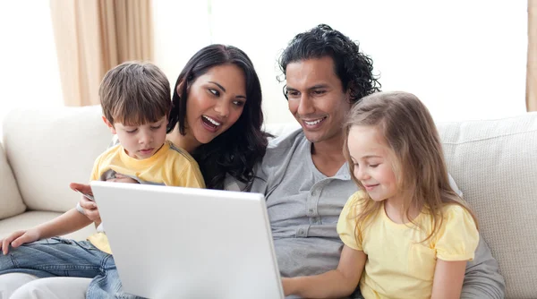 Met behulp van laptop op sofa en gelukkige familie — Stockfoto