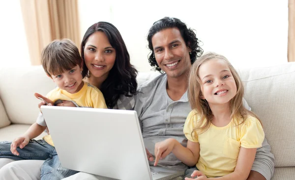 Família alegre usando laptop no sofá — Fotografia de Stock