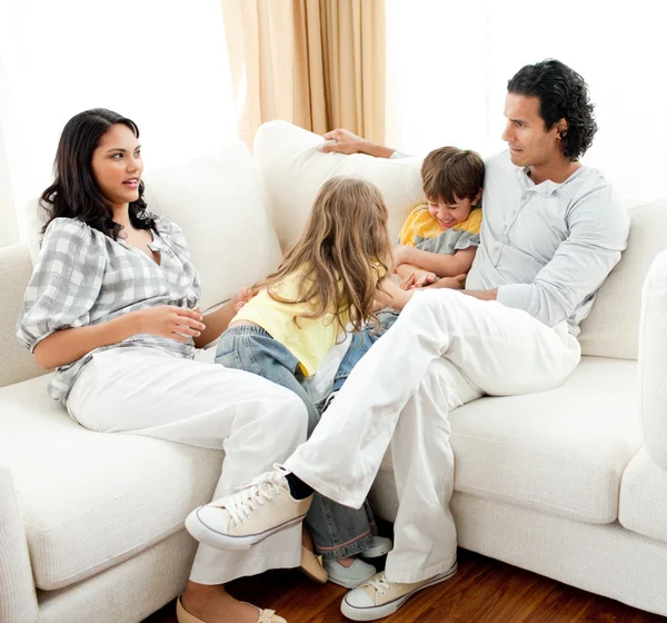 Внимательные родители сидят на диване со своими детьми — стоковое фото