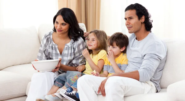 Leende familjen tittar på tv soffan — Stockfoto