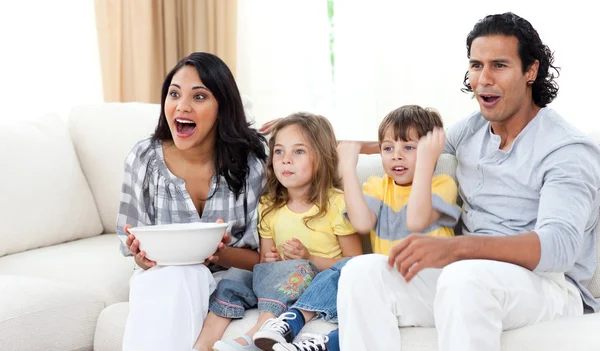 Nette Geschwister vor dem Fernseher mit ihren Eltern — Stockfoto