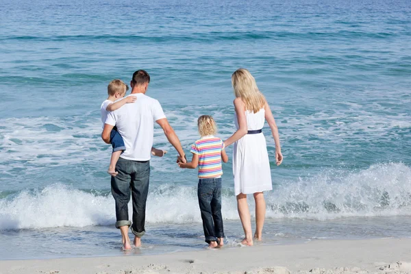 Família feliz andando na areia — Fotografia de Stock