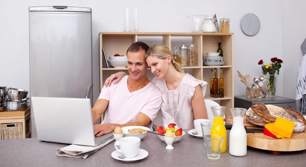 Lyckliga paret använder en bärbar dator samtidigt ha frukost — Stockfoto