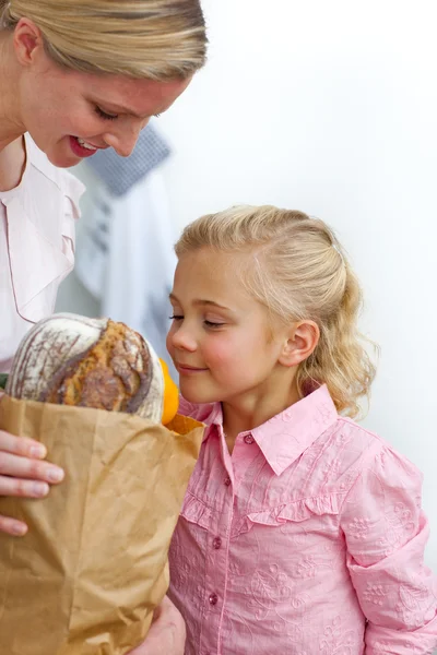 Sonriente madre y su hija desempacando la bolsa de comestibles —  Fotos de Stock
