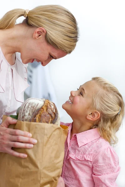 Lachende moeder en haar dochter uitpakken kruidenier zak — Stockfoto