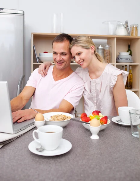 Увлекательная пара, использующая ноутбук во время завтрака — стоковое фото
