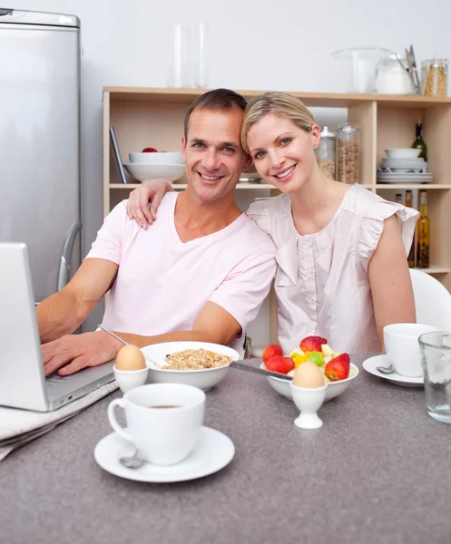 Casal afetuoso usando um laptop enquanto toma café da manhã — Fotografia de Stock
