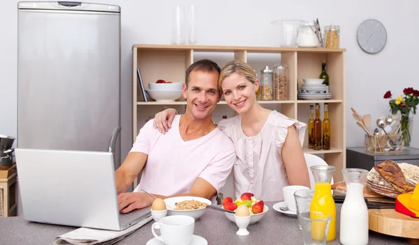 Casal jovem usando um laptop enquanto toma café da manhã — Fotografia de Stock