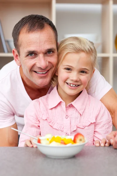 Niña feliz comiendo fruta con su padre — Stockfoto