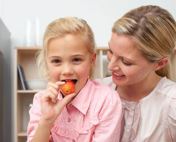 Lively little girl eating fruit with her mother — Stock Photo, Image