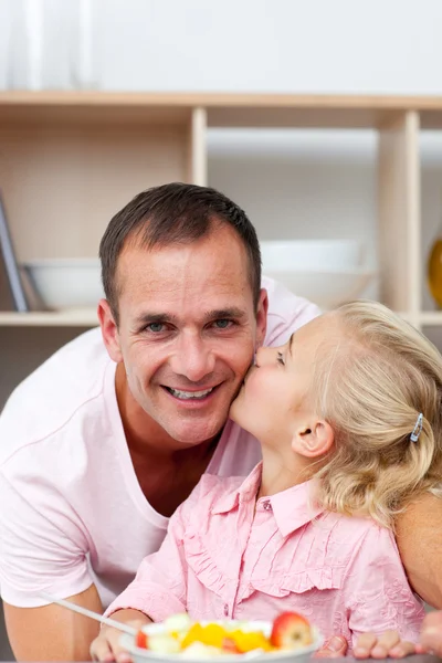 Cute little girl eating fruit with her father — Stock Photo, Image