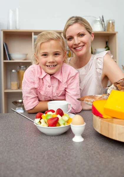 Caring mother eating fruit with her daughter — Stock Photo, Image