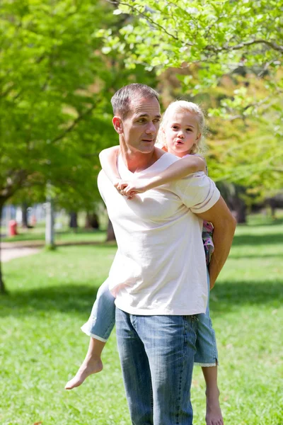 Радостный отец катает свою дочь на спине — стоковое фото