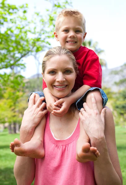 Glada mor att hennes son piggy-back ride — Stockfoto