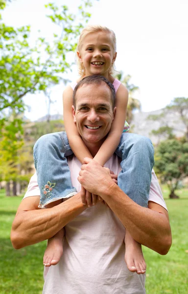Улыбающийся отец катает свою дочь на спине — стоковое фото