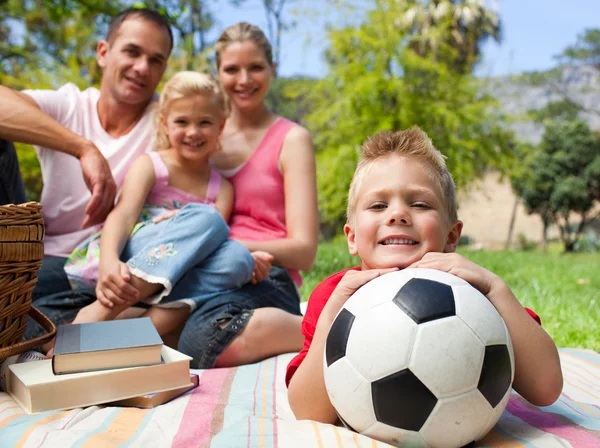 Piccolo ragazzo divertirsi con un pallone da calcio con la sua famiglia sorridente — Foto Stock