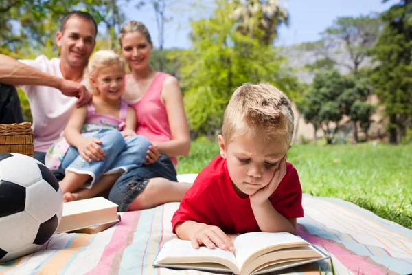 Concentrated blond boy reading while having a picnic with his fa — Stock Photo, Image