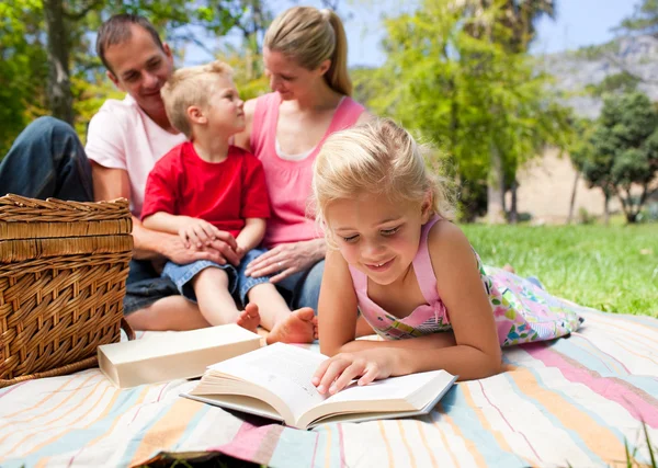 Серйозна маленька дівчинка читає під час пікніка — стокове фото