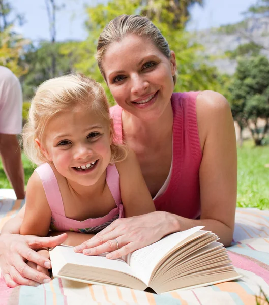 Feliz madre y su hija leyendo en un parque —  Fotos de Stock