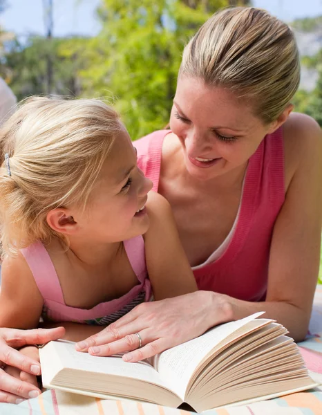 Portrait of a smiling mother and her daughter reading at a picni — Stock Photo, Image