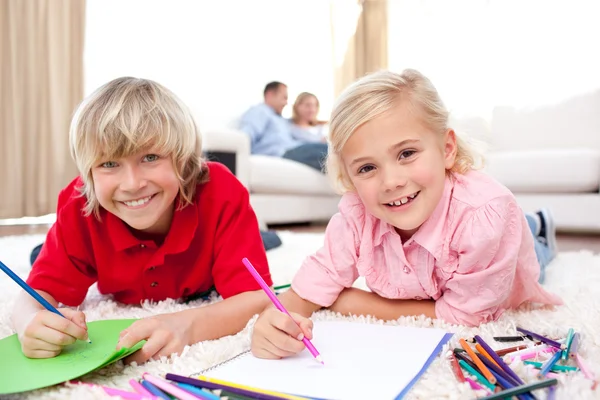 Lively siblings drawing lying on the floor — Stock Photo, Image