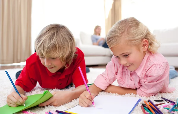 Adorable siblings drawing lying on the floor — Stock Photo, Image