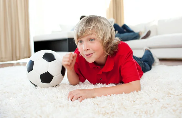 Glada pojke tittar på fotbollsmatch liggande på golvet — Stockfoto