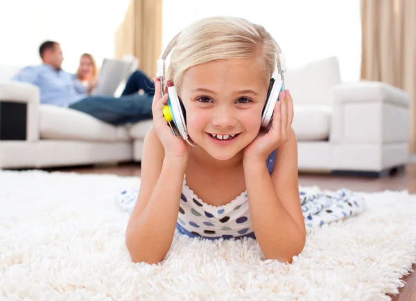 Boldog kis lány hallgat zenét feküdt a padlón — Stock Fotó