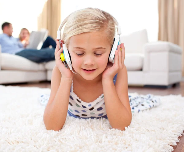 Aranyos kis lány hallgat zenét feküdt a padlón — Stock Fotó