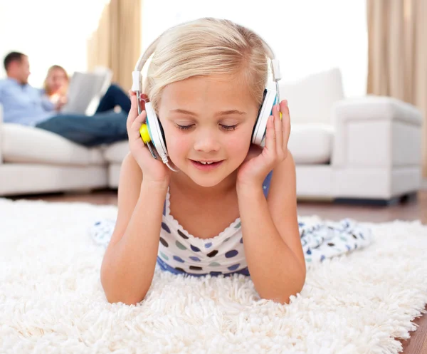 Linda niña escuchando música tumbada en el suelo — Foto de Stock