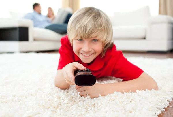 Rapaz alegre assistindo TV deitado no chão — Fotografia de Stock
