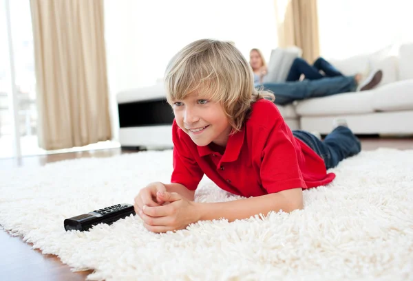 Konzentrierter Junge sieht Fernseher auf dem Boden liegend — Stockfoto