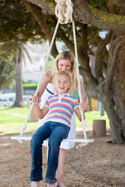 Mère heureuse poussant sa fille sur une balançoire — Photo