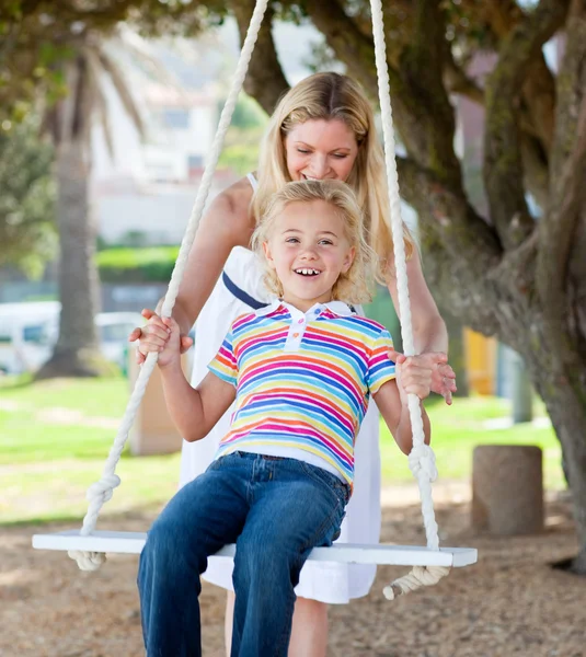 Alegre madre empujando su hija en un swing —  Fotos de Stock