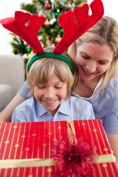 Lachende moeder en haar zoon openen kerstcadeau — Stockfoto