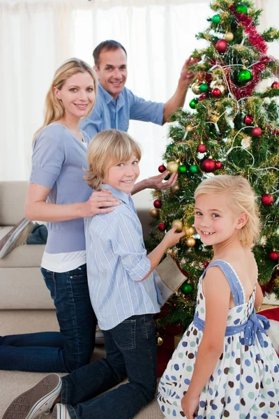 Lächelnde Familie schmückt einen Weihnachtsbaum — Stockfoto