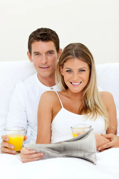 Young couple reading a newspaper and drinking orange juice — Stock Photo, Image
