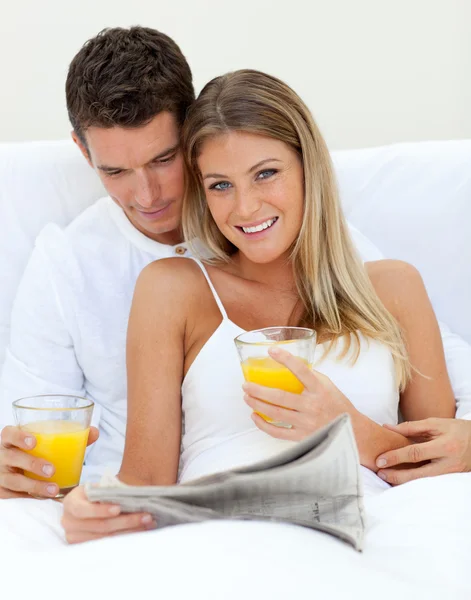 Amante casal lendo um jornal e beber suco de laranja — Fotografia de Stock