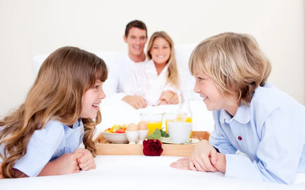 Cheerful family having breakfast sitting on bed — Stock Photo, Image