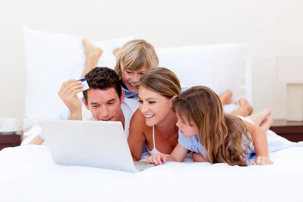 Familia animada comprar en línea acostado en la cama — Foto de Stock