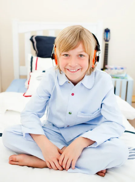 Cute boy listening music sitting on bed — Stock Photo, Image