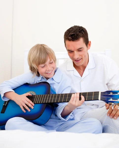 Garotinho sorridente tocando guitarra com seu pai — Fotografia de Stock
