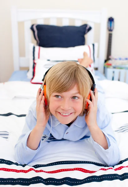 Розслаблений хлопчик слухає музику, що лежить на ліжку — стокове фото