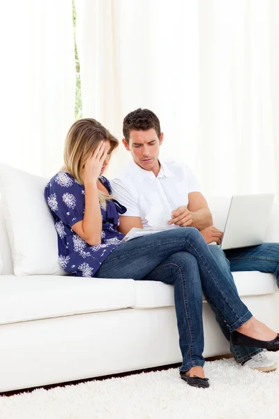 Занепокоєна пара робить свої рахунки, сидячи на дивані — стокове фото