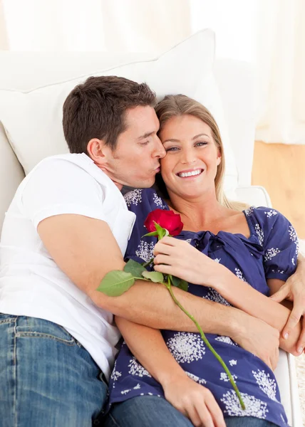 Homem afetuoso beijando sua esposa deitado no sofá — Fotografia de Stock