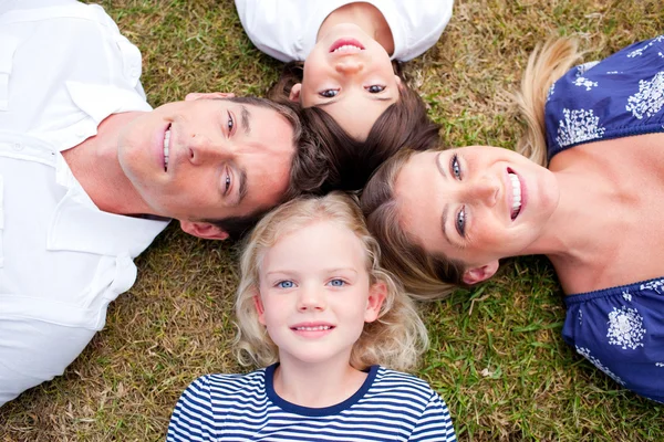 Liebevolle Familie liegt im Kreis auf dem Gras — Stockfoto